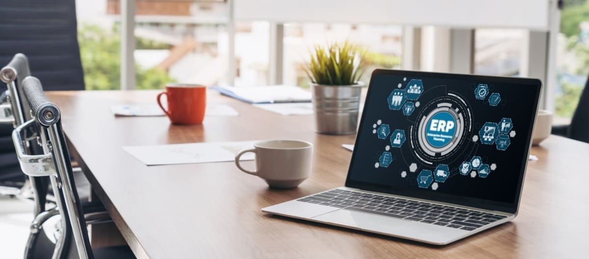 A laptop on a table with ‘ERP’ on the screen