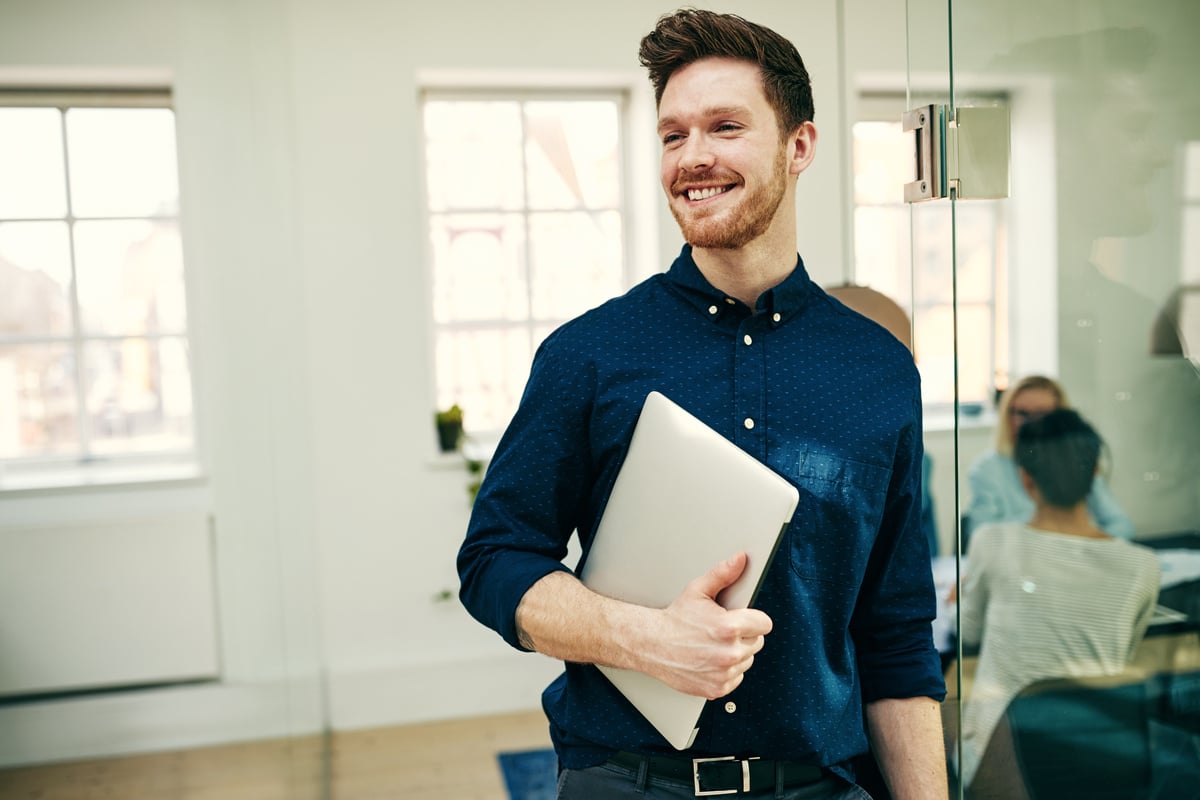 A man holding a laptop in a modern office