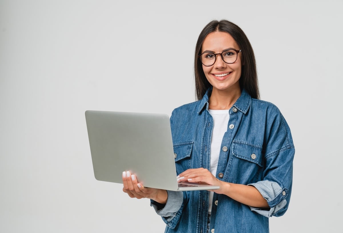 A woman holding a laptop and smiling