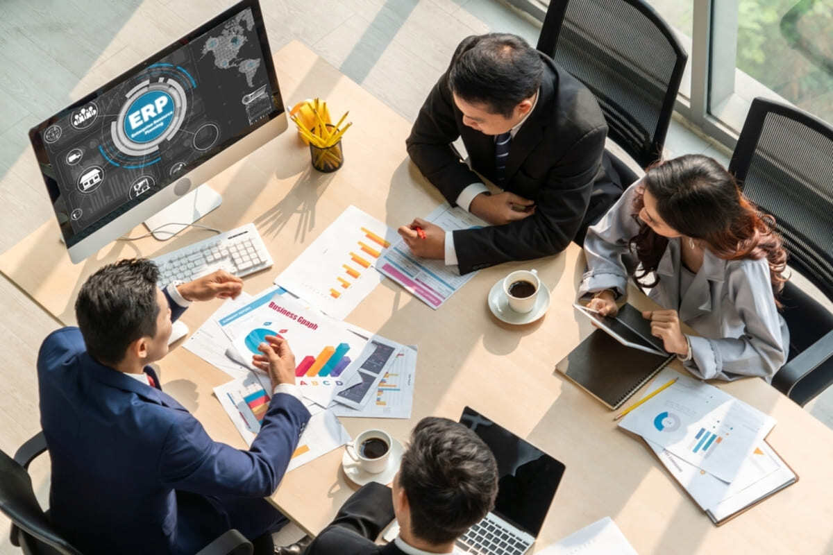 Four people sat at a table having an ERP software business meeting