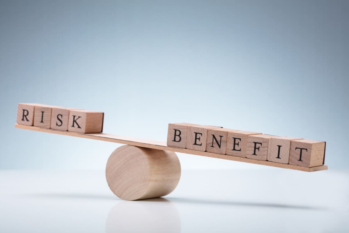 Wooden blocks on a scale that spells benefits and risks