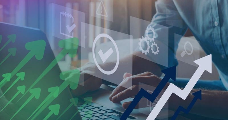 Double exposure of hands on laptop and graphs showing arrows going up