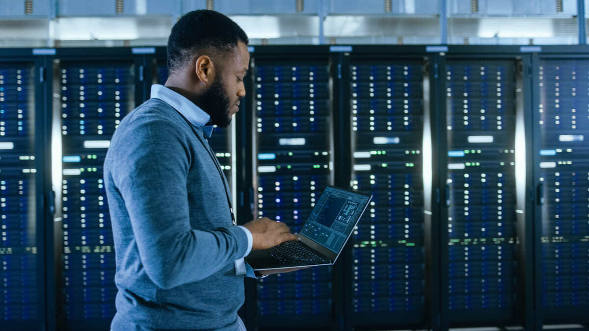 A person working on a laptop next to servers, managed IT service concept