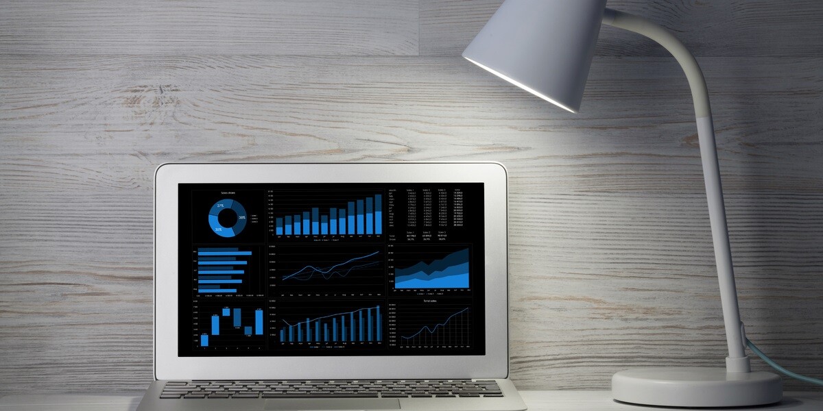 Graphs and data on a laptop next to a lamp